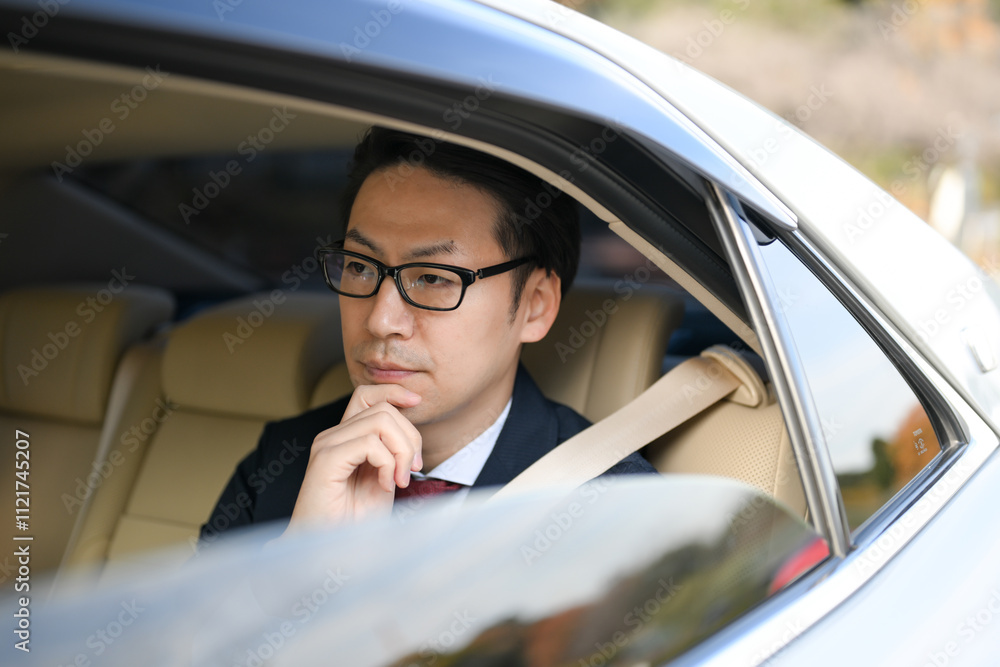 車の後部座席に乗るビジネスマン 車の後部座席に乗るビジネスマン
