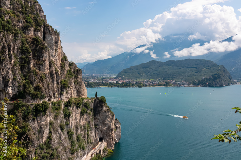 Hiking and cyclist trail Sentiero del Ponale with scenic view of Garda Lake, Trentino, Northern Italy. Steep rugged cliffs of majestic mountains of Garda Hills. Summer travel vacation in Italian Alps