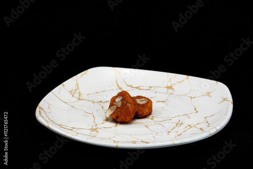 Two portions of Mohanthal, a traditional sweet from Gujarat, are presented on a white plate photo