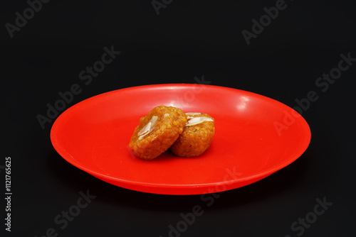 Two pieces of a Gujarati sweet Mohanthal on small red dish photo