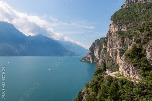 Hiking and cyclist trail Sentiero del Ponale with scenic view of Garda Lake, Trentino, Northern Italy. Steep rugged cliffs of majestic mountains of Garda Hills. Summer travel vacation in Italian Alps