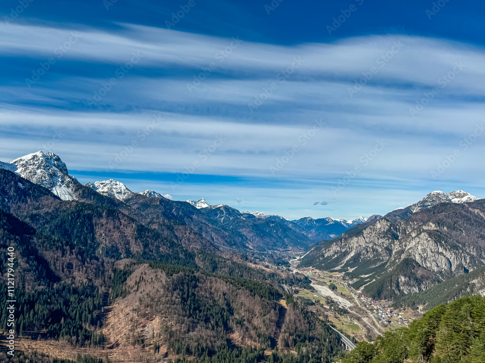 Fototapeta premium Aerial view of valley Val Canale and alpine village Malborghetto Ugovizza surrounded by snow capped mountains peaks of Julian and Carnic Alps, Friuli Venezia Giulia, Italy. Wanderlust Italian Alps