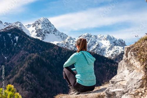 Hiker woman with panoramic view of snow capped mountain peaks of Julian Alps seen from Monte Nebria, Friuli Venezia Giulia, Italy. Wanderlust in alpine wilderness in early spring. Positive emotions photo