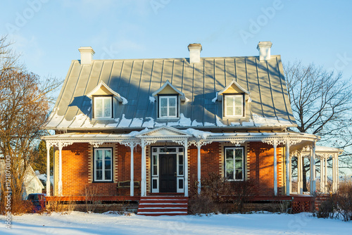 
Quaint red brick patrimonial house with steep metal roof and black door seen during a winter morning, Saint-Nicolas, Quebec, Canada