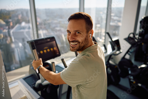 Happy athlete exercising on cross trainer and looking at camera. photo