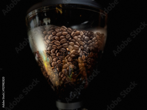 Close-Up of Coffee Beans in Hopper with Dark Background. Detailed view of roasted coffee beans inside a grinder hopper, with a soft focus effect and dark background, perfect for coffee-related themes