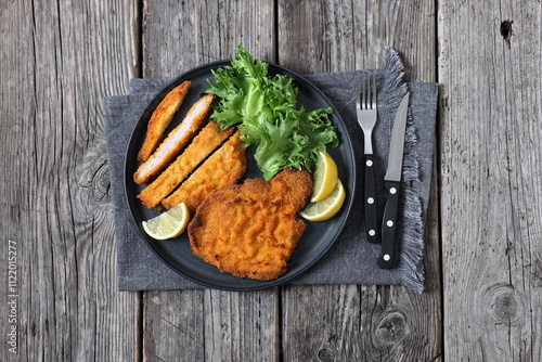 Foto Pork Milanese with lettuce and lemon on a plate