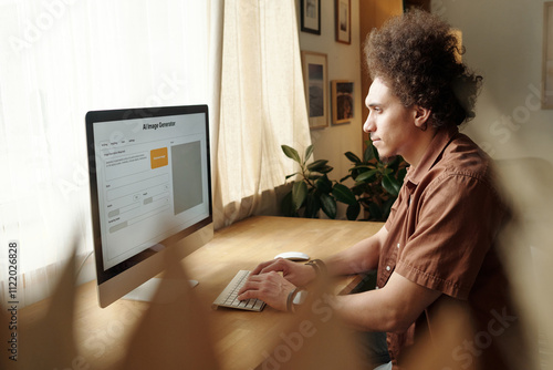 Side view of young male home office designer looking at computer screen with visual language model photo