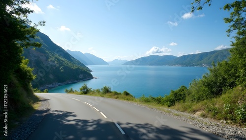 Scenic coastal drive along the tranquil blue waters under a clear sky near the mountains