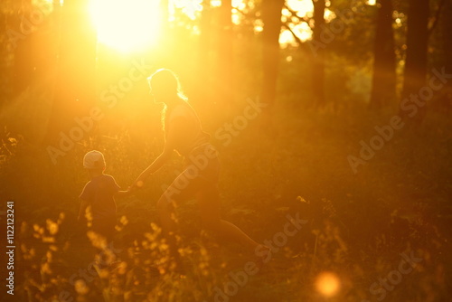 mom and child run against the sun, silhouettes bathed in light