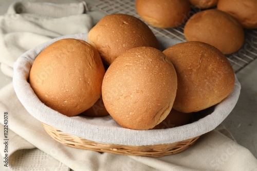 Fresh tasty buns in basket on table, closeup