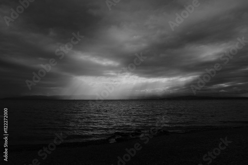 A stunning black-and-white view of the lake under dramatic clouds, with rays of sunlight breaking through. A peaceful moment captured by the water