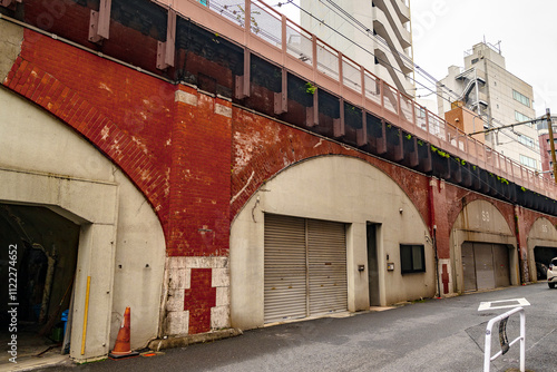 Historic Koyanagi Bridge Viaduct with Red Brick Arches, Now Repurposed as Storage Facilities, Under Elevated Train Line (Tokyo, Japan ‐ December 2024) photo