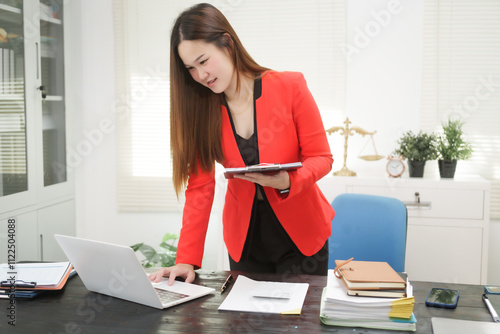 A cheerful businesswoman works at her office desk as a legal consultant, handling online civil cases, including debt disputes, unfair dismissals, foreclosures, land redemptions, with professionalism photo