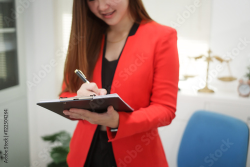 A cheerful businesswoman works at her office desk as a legal consultant, handling online civil cases, including debt disputes, unfair dismissals, foreclosures, land redemptions, with professionalism photo