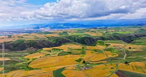 Yellow and green wheat fields natural landscape on top of mountain. Beautiful farmland scenery in Jiangbulake Scenic Area, Xinjiang, China. photo