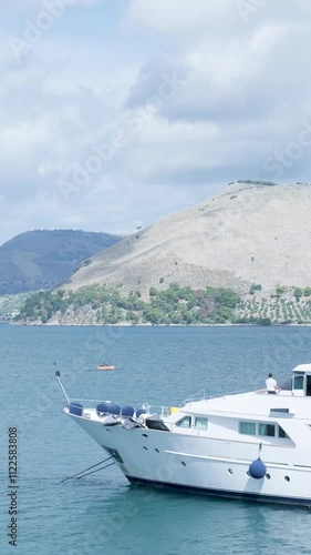 Captain stands on the deck of his yacht, looking out at the horizon