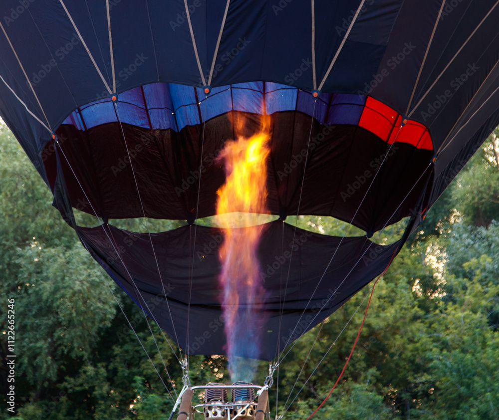 Obraz premium A hot air balloon with a red and orange striped body is floating in the sky
