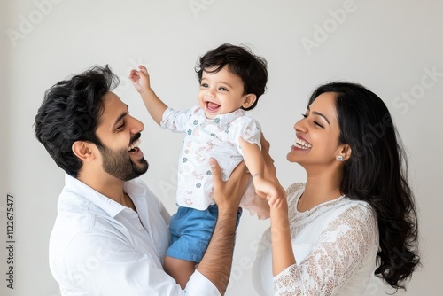 A happy south asian family of three: a father carrying his one-year-old son on his shoulders, while a smiling mother sits in beside them