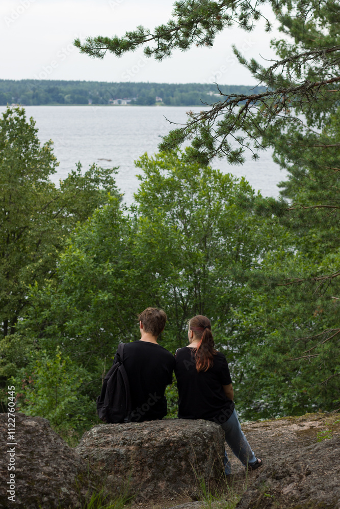 A couple sits on a rock overlooking a river. Vyborg. A couple sits on a rock overlooking a river. Vyborg.