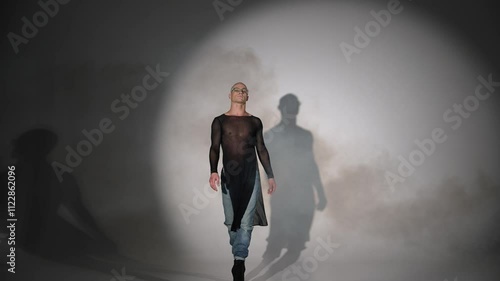 Male actor walking on improvised stage in women's shoes. Modern male dancer posing in photo studio. Male gait in women's shoes.