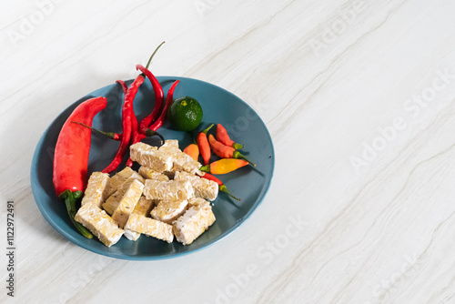 Side view of food background with chili, lime, and tempeh on marble background
