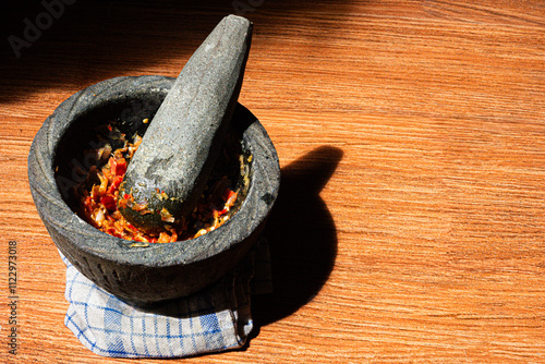 The stone mortar and pestle are traditional cooking tools for griding spices. Side view