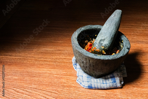 The stone mortar and pestle are traditional cooking tools for griding spices. Side view