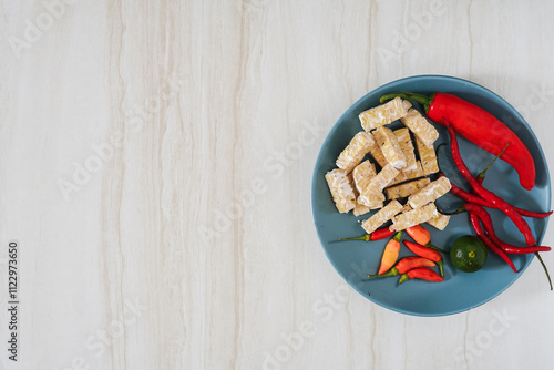 Top view of food background with chili, lime, and tempeh on marble background