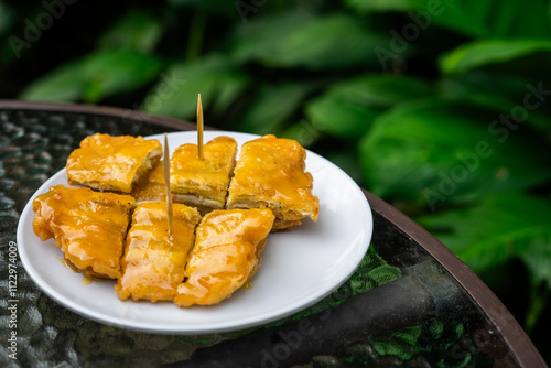 Side view of a signature dish of Pontianak, Indonesia called srikaya fried banana on a glass table