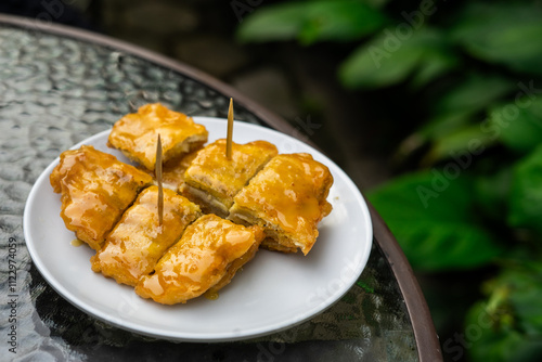 Side view of a signature dish of Pontianak, Indonesia called srikaya fried banana on a glass table