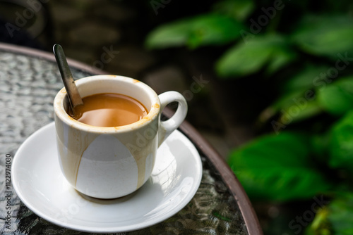 A cup of coffee milk on a glass table with a natural background in the morning