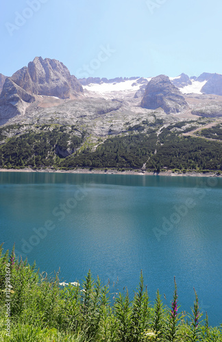 High above, Mount Marmolada overlooks the glacier which, melting, forms the artificial Lake Fedaia photo