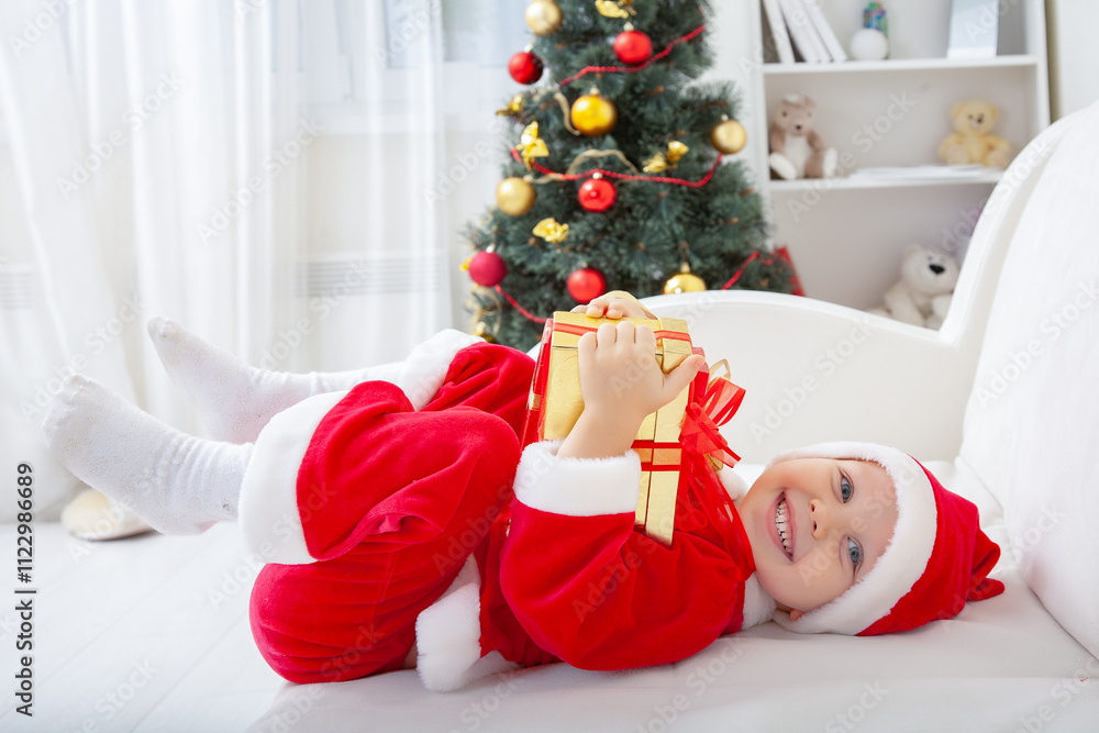 Portrait of little cute boy in Santa Claus costume with Christmas present