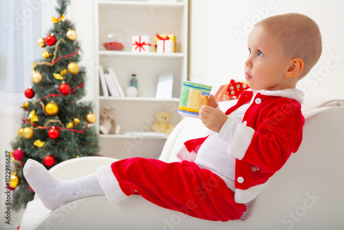 Obraz na płótnie Portrait of little cute boy in Santa hat drinking milk with biscuit w salonie