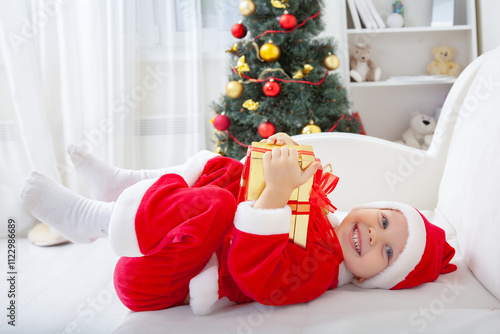 Portrait of little cute boy in  Santa Claus costume  with Christmas present