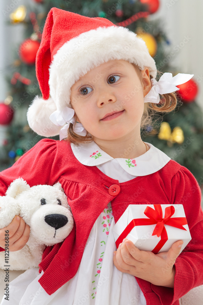 Portrait of little cute girl in Santa Claus costume with Christmas present