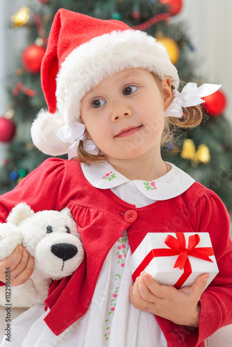 Obraz na płótnie Portrait of little cute girl in Santa Claus costume with Christmas present w salonie