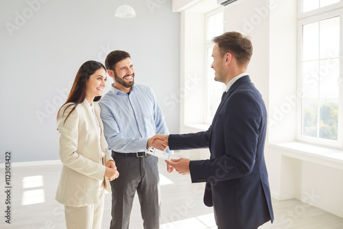 Family couple shakes hands with a real estate agent or realtor, sealing an agreement on a new home purchase. Handshake represents trust and the successful finalization of a property deal. photo