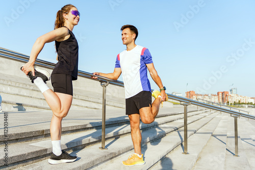 Two people stretching on outdoor stairs in a sunny urban setting before a workout session photo