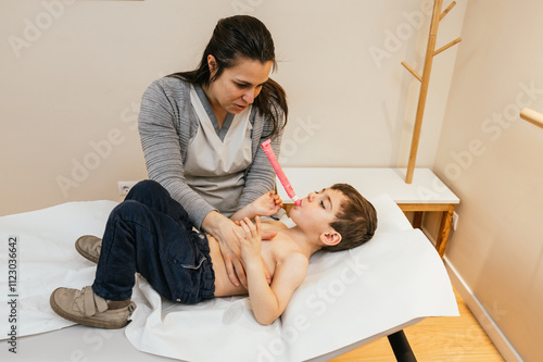 Foto Physiotherapist assisting young boy with respiratory physiotherapy using pep mas