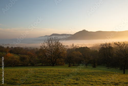 Herbst - Nebel im Albvorland. Schwäbischer Albtrauf zum Sonnenaufgang. Blick Richtung Nordost auf die Burgfestung Hohenneuffen. Im Tal bedeckt der Nebel die Ortschaft Neuffen. photo