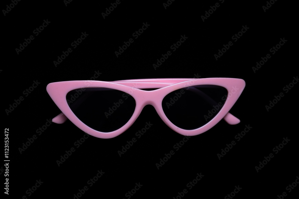 pink cat eye sunglasses lying on black background