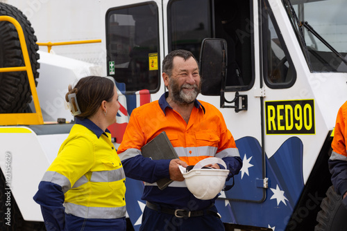 Workers in high visibility clothing standing beside australian crane truck on industrial site photo