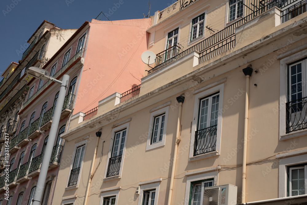 Naklejka premium A row of colorful buildings with balconies and windows casting long shadows