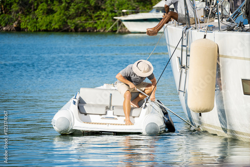 Male deckhand with a hat washing a sailing superyacht at dock in Antigua, island in the caribbean on a sunny day