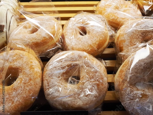 Sugar coated donut for sale. Sugar coated donut in plastic wrap on wooden tray for sale