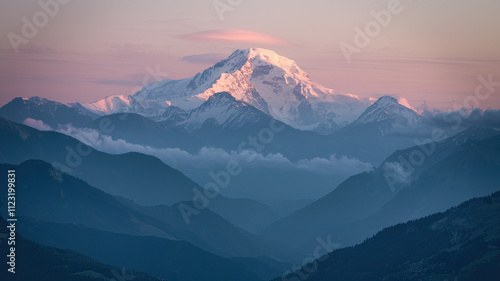 A breathtaking mountainous landscape during dawn or dusk dominated by a majestic snow-capped peak bathed in golden sunlight surrounded by misty mountain ranges with dense forests