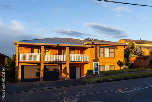 sunlight on brick home with garages and balcony on hillside in Wallsend photo