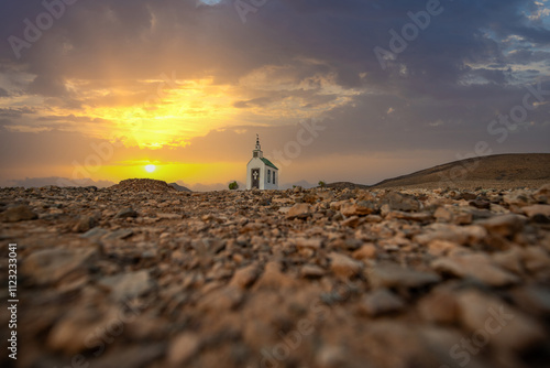 small cute white wooden chapel in a barren volcanic landscape. Sunrise, landscape shot of Ermita Protestante de Violante church, on Fuerteventura island, Canary Islands, Spain